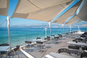 a row of tables and chairs with the ocean in the background at Grand Hotel View in Postira