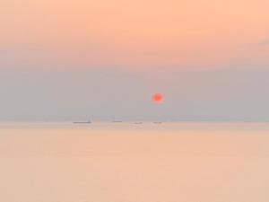 eine orangefarbene Sonne am Himmel über dem Ozean in der Unterkunft Moon's Diving House in Green Island