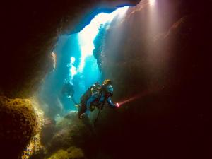 a diver in a cave with a light illuminating the water at Moon's Diving House in Green Island