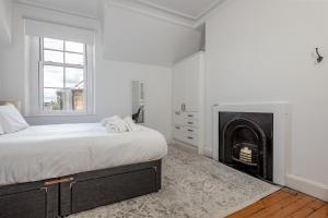 een witte slaapkamer met een bed en een open haard bij Oakwood House - Sleeps 6 - St Andrews in St Andrews