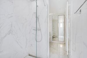 W białej łazience z przeszklonymi drzwiami znajduje się prysznic. w obiekcie Cosy apartment 4P-1BR Flandre-Crimée w Paryżu +4 zdjęcia