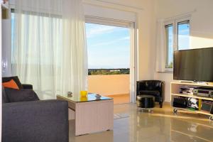 a living room with a couch and a flat screen tv at Olive Tree Hillside Apartment in Stalos
