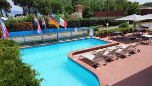 uma piscina com cadeiras, guarda-sóis e bandeiras em Residence Ranieri em Castiglione del Lago