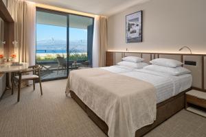 a hotel room with a large bed and a table and chairs at Grand Hotel View in Postira