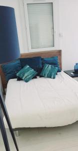 Bett mit blauen Kissen auf einem Zimmer in der Unterkunft La Cigale de Mer à 100 m de la Plage et du Centre Ville du Grau du Roi in Le Grau-du-Roi