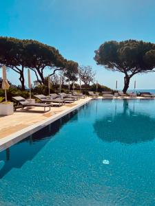 a swimming pool with chaise lounge chairs and trees at Resort Capo Bianco in Porto Azzurro