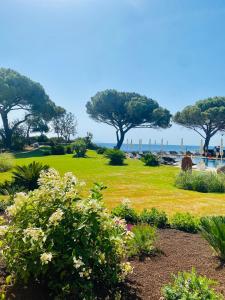 a park with green grass and trees and the ocean at Resort Capo Bianco in Porto Azzurro