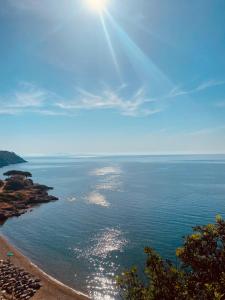 una vista del océano con el sol brillando en el agua en Resort Capo Bianco, en Porto Azzurro