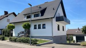 uma casa branca com um telhado preto em Apartment nähe Ettlingen - 15 min zur Messe Karlsruhe em Malsch