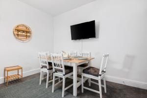 a dining room with a table with chairs and a tv at Modern Tree View House- TV in every Bedroom! in Morriston