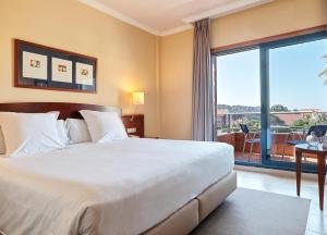 a bedroom with a large bed and a large window at Hotel Spa Galatea in Portonovo