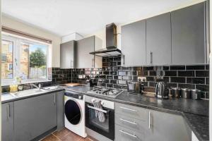 a kitchen with a washing machine and a sink at ◑4 Bed Townhouse◑10guests◑ Garden◑Wifi & Netflix◑ in Thamesmead