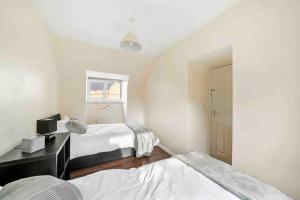 a bedroom with two beds and a window at ◑4 Bed Townhouse◑10guests◑ Garden◑Wifi & Netflix◑ in Thamesmead