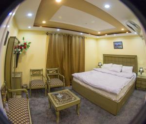 a bedroom with a bed and two chairs and a table at Ringchan Guest House & Restaurant in Skardu