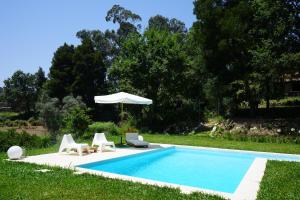 una piscina con due sedie e un ombrellone di Quinta do Vale Grande ad Albergaria-a-Velha