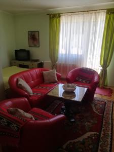 uma sala de estar com um sofá de couro vermelho e uma mesa em Apartman Monika Zlatar Nova Varos em Nova Varos