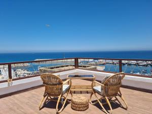 un balcón con 2 sillas, una mesa y el océano en Splendide duplex à MDIQ avec vue panoramique, en M'diq