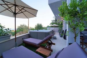balcón con banco, bañera de hidromasaje y sombrilla en Moonlight Suites, en Parga