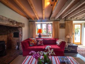 a living room with a red couch and a fireplace at Country Cottage with Spa, Catering, Gardens, Nature Reserve Walks - Free Parking, Self Checkin in Scunthorpe