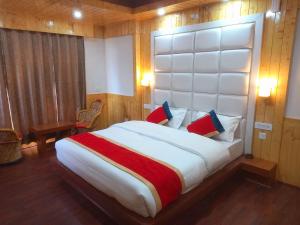 a bedroom with a large bed with a large headboard at Humble Holiday Inn Kufri Simla in Shimla