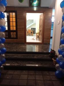 una puerta que conduce a una habitación con globos azules y blancos en God's gift en Devikolam