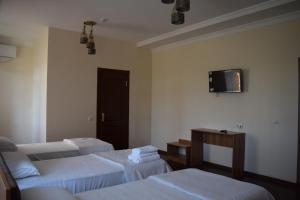 a room with three beds and a tv on the wall at Hotel SUZUK-OTA in Tashkent