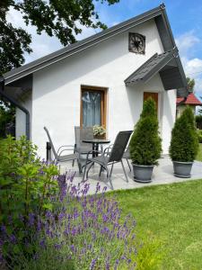 a white cottage with a table and chairs in the yard at Eko Dolina Kluki in Kluki
