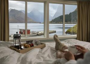 una persona tumbada en la cama mirando por la ventana en Sagafjord Hotel - by Classic Norway Hotels en Sæbø