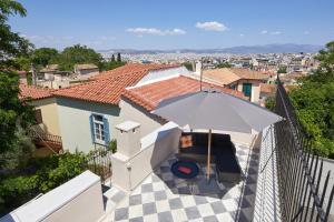 um pátio com um guarda-chuva e uma mesa em Muazzo Plaka Homes, Ground Home No Balcony & Upper Home with Balcony, by ThinkVilla em Atenas