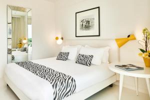 Mondial Resort & Spa في مارينا دي بيتراسانتا: غرفة نوم بيضاء مع سرير مع وسائد حمار الوحشي