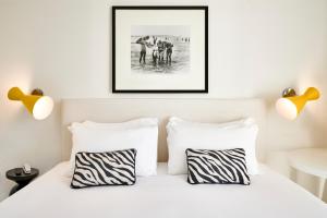 a white bed with two pictures on the wall at Mondial Resort & Spa in Marina di Pietrasanta