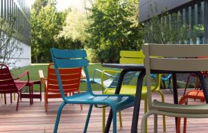 un grupo de sillas y mesas coloridas en una terraza en sylc. Apartmenthotel – Serviced Apartments, en Hamburgo