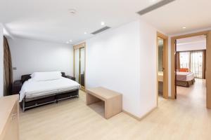 a white bedroom with a bed and a table at Hotel Cristina by Tigotan Las Palmas - Adults Only in Las Palmas de Gran Canaria