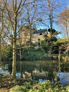 a house on a hill next to a body of water at Grande maison de charme, 14 pers. 5 chambres, sauna, écrin de verdure, baby foot in Saint-Clémentin