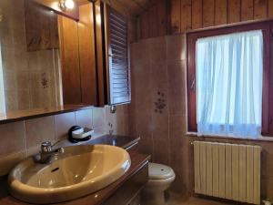 Un baño con lavabo, inodoro y ventana. en Peace and Lake Mountain Lake Iseo Hospitality, en Bossico