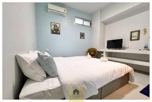 a bedroom with a bed with white sheets and a tv at Hooman Hostel in Chiang Mai