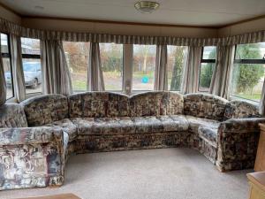 a couch sitting in a living room with windows at Chalet Westmoreland in De Pol