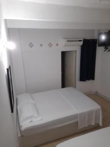 a small bedroom with a white bed and a window at Rivera Hostel in Santa Marta