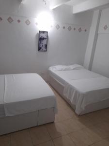 two beds in a room with white walls at Rivera Hostel in Santa Marta