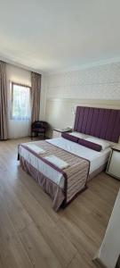 a large bedroom with a large bed with a purple headboard at Bronze Hotel in Gümbet