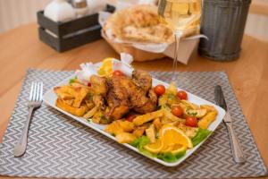 a plate of food with chicken and french fries and a glass of wine at Seva Hotel Health Club in Câmpina