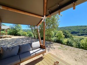 een bank op een veranda met uitzicht op een veld bij Tente Cottage (6p) Fécamp Etretat in Colleville