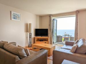 a living room with a couch and a flat screen tv at Sunset Surf - Mount Brioni in Downderry