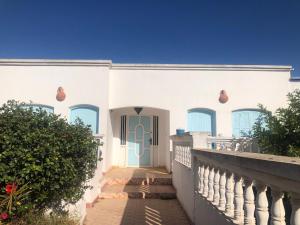 ein weißes Haus mit einer blauen Tür und einer Treppe in der Unterkunft Dar SAADA maison de sylvie in Souira Guedima