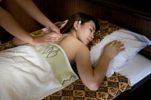 a woman laying on a bed with a woman getting her pantiespeed at Jakarta Airport Hotel in Tangerang