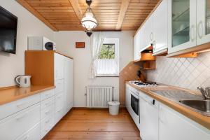 a kitchen with white cabinets and a wooden floor at Primula Cottage, a step away from Kranjska Gora in Kranjska Gora