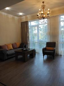 a living room with a couch and a table and a chandelier at Apartment Likani in Borjomi