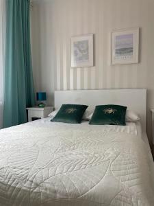a bedroom with a white bed with two green pillows at Pokój dla dwojga w zacisznej części Sopotu z łazienką wspólną dla dwóch pokoi in Sopot