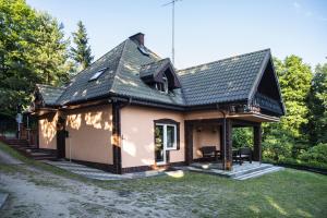 ein kleines Haus mit schwarzem Dach in der Unterkunft U Lipińskich - Dom nad jeziorem in Ostrzyce