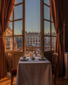 a table with a view of the louvre from a window at Grand Hotel De La Reine - Place Stanislas in Nancy